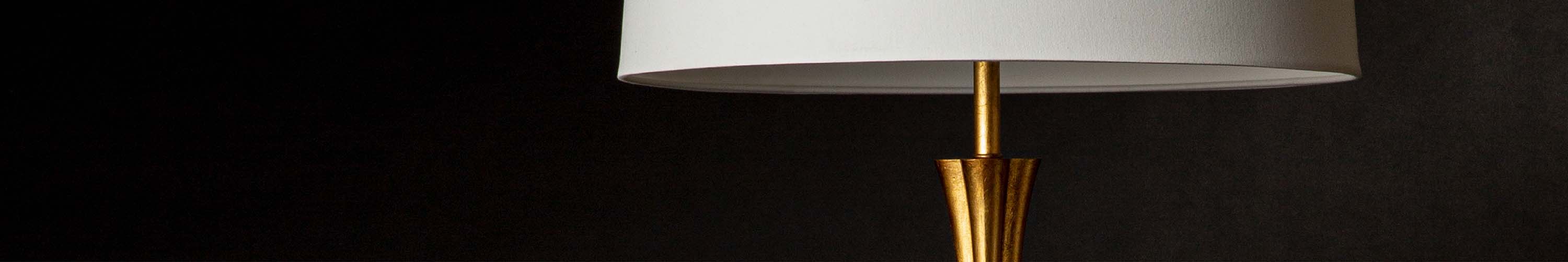 Gold floor lamp with white shade on a black background